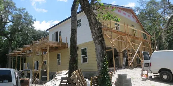 17 Oaks Plantation — exterior scaffolding with yellow siding and white trim nearing completion